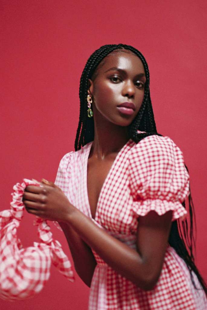 Black woman wears red and pink Tilda dress from Molby the label and red gingham bag 