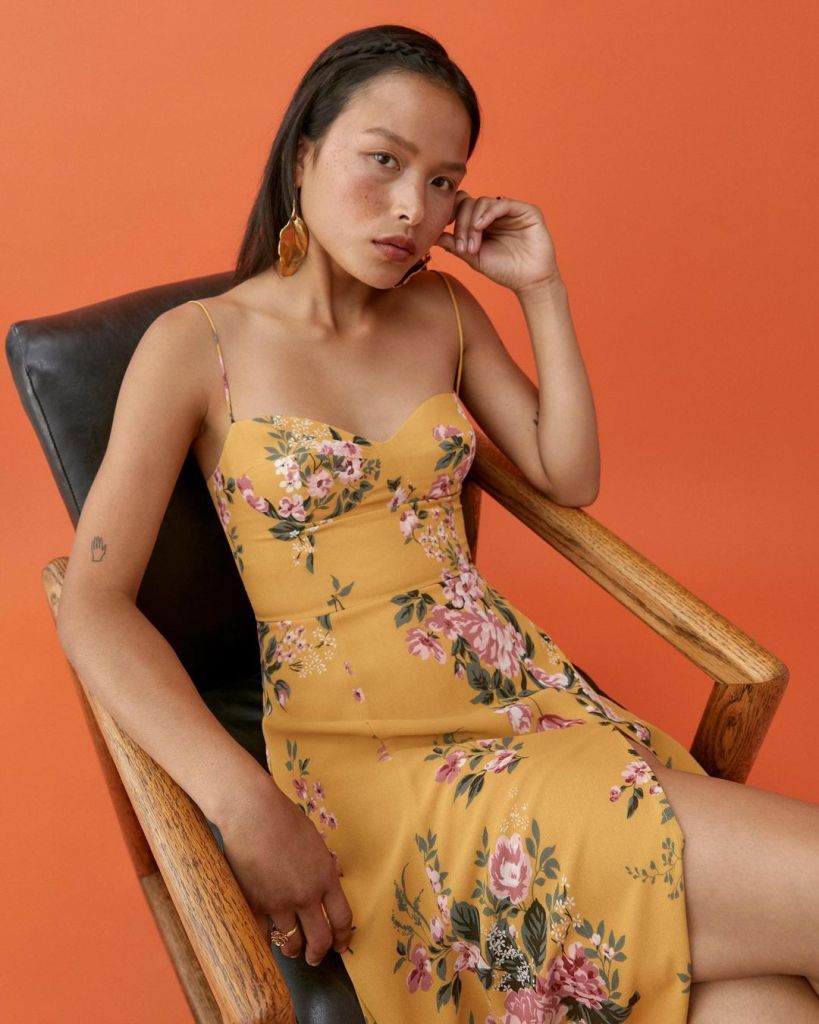 A Reformation model wearing a yellow floral dress.