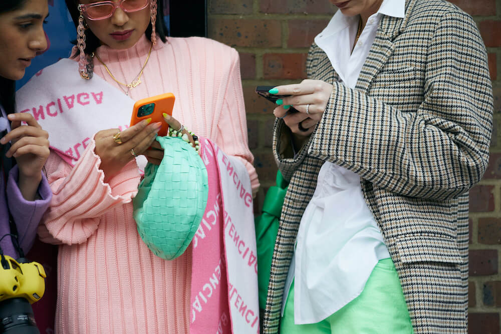 Two women at fashion week holding Bottega Veneta handbags