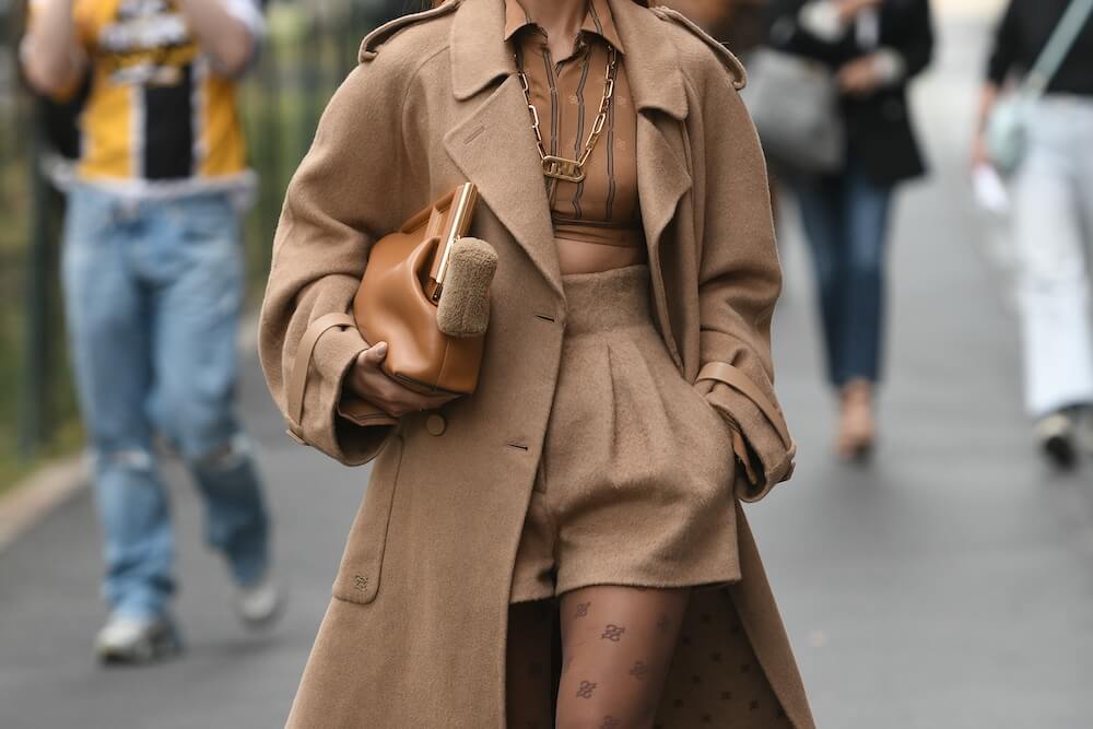 woman wearing an all brown ensemble: wool coat, crop top, and wool trousers