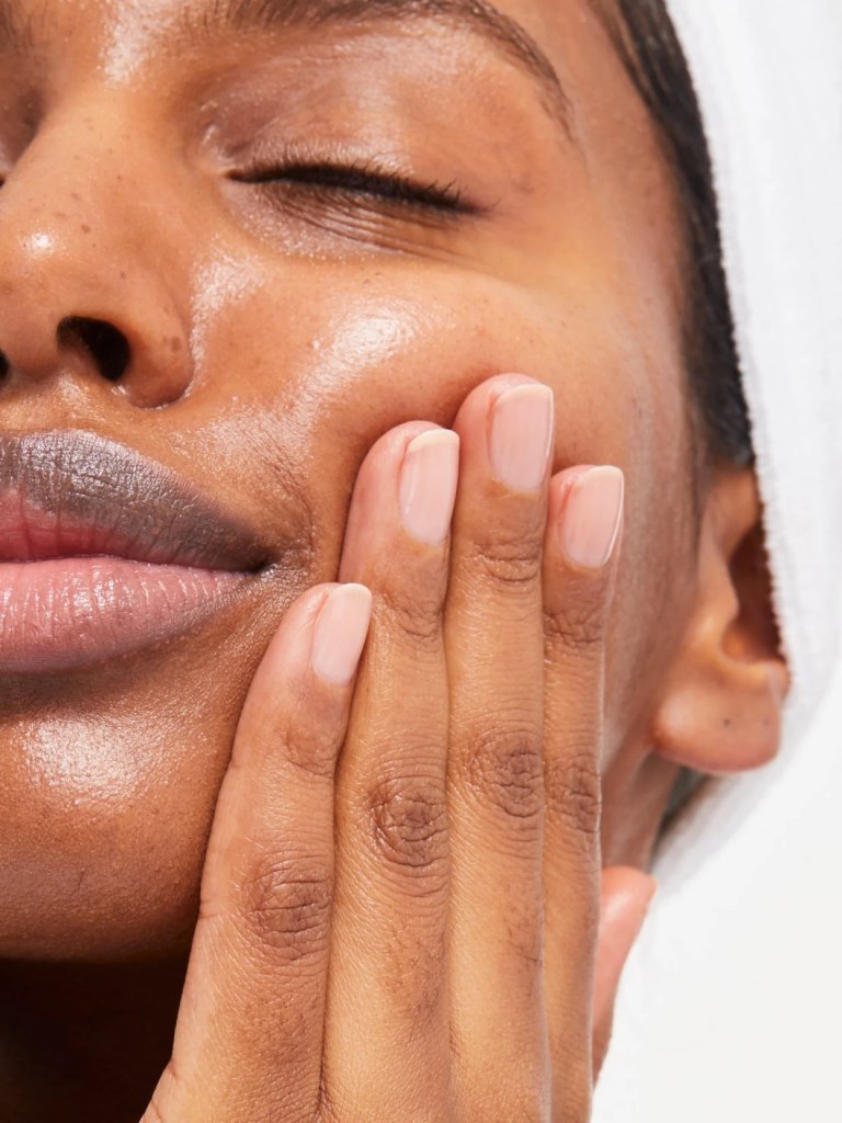 woman putting Glossier products on her face