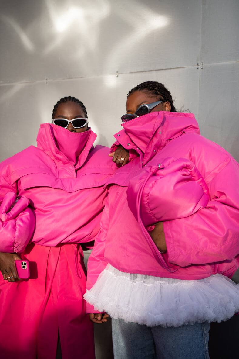 two black women wear fuchsia pink puffer jackets at copenhagen fashion week