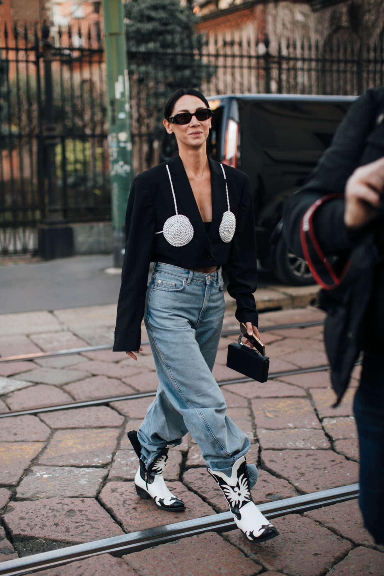 Woman at fashion week wears cowboy boots tucked into denim jeans