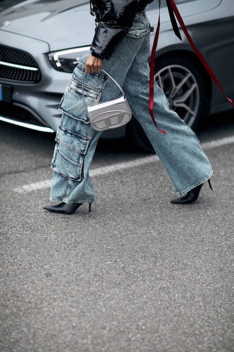 woman at fashion week wears cargo jeans and heeled boots