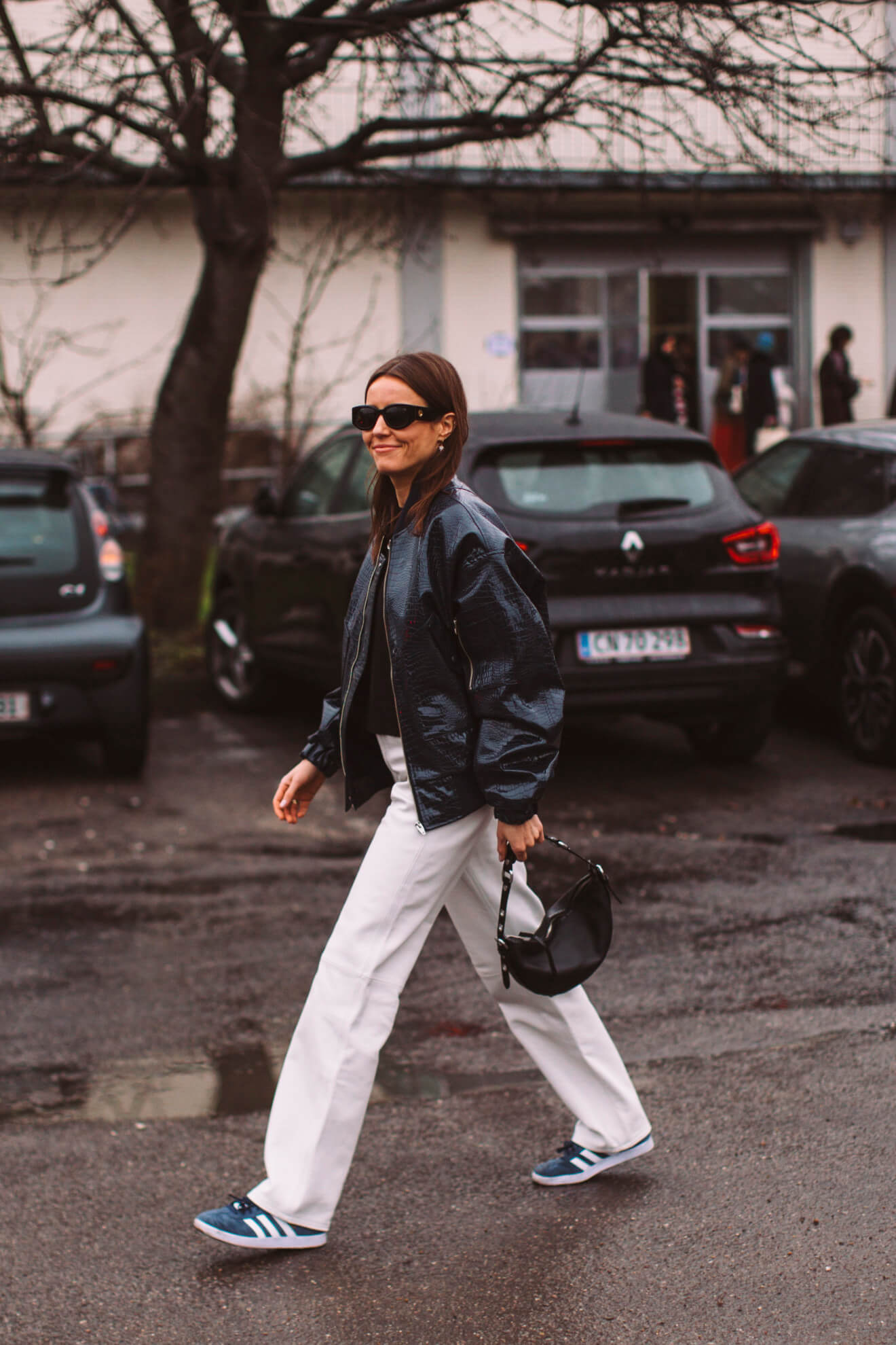 woman wears flared jeans and adidas sambas at fashion week
