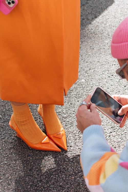 Person takes a photo of friend's prada orange shoes at london fashion week